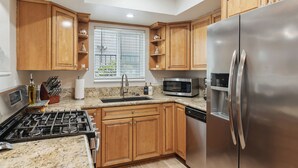 A kitchen with wooden cabinets, stainless steel appliances, a gas stove, a microwave, and a refrigerator. - New! Refreshing Beach Getaway- Heart of San Diego! (San Diego)