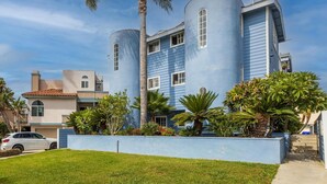 A modern building with cylindrical towers and a blue facade, surrounded by well-maintained landscaping and a parked car. - New! Refreshing Beach Getaway- Heart of San Diego! (San Diego)