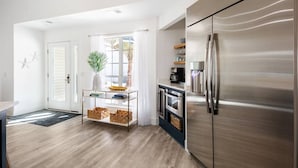Een moderne keuken met een roestvrijstalen koelkast, een inbouwoven en een koffiehoek met glazen plaat.