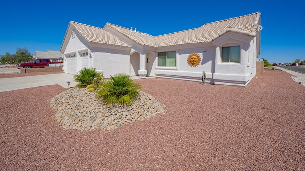 A single-story house with a tiled roof, a garage, and a small garden with cacti and rocks. - Mohave desert retreat  (Fort Mohave)