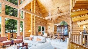 L’intérieur d’une cabane en rondins comprend un salon, un coin repas et de grandes fenêtres.