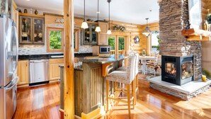 Une cuisine spacieuse avec des meubles en bois, une cheminée en pierre et un coin bar.