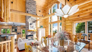 Une cabane en bois spacieuse comprenant un coin repas, une cuisine et un salon.