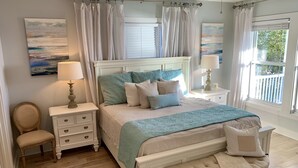 Un dormitorio con una cama grande, una mesita de noche, una silla y una ventana con cortinas.