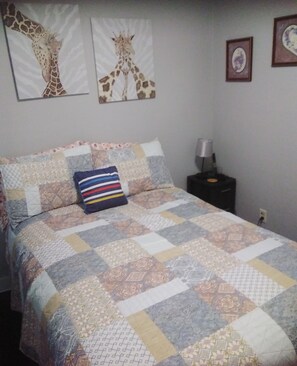 A bedroom with a quilted bedspread, a striped pillow, and two giraffe-themed wall art pieces. - Convenient Family-Friendly Home -10 Min to Tulsa!" (Tulsa)