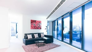Een moderne woonkamer met een zwarte modulaire bank, een ronde salontafel en een groot raam met uitzicht op de stad.