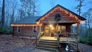A wooden cabin with a porch, steps, and a wreath on the front door.