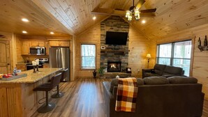 A log cabin interior with a kitchen, dining area, and living room.