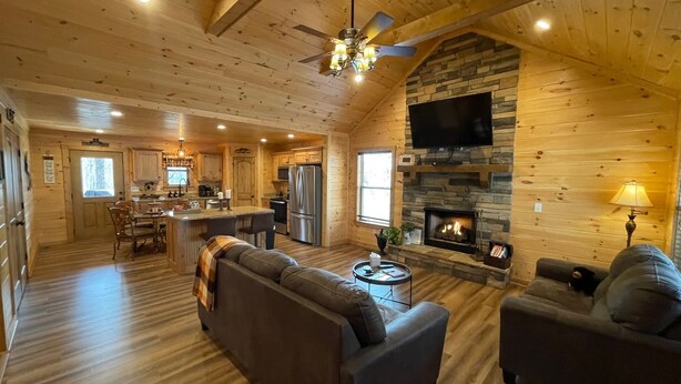 A cozy log cabin interior with a living room, kitchen, and dining area.