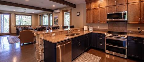 A modern kitchen with granite countertops, stainless steel appliances, and dark cabinetry.