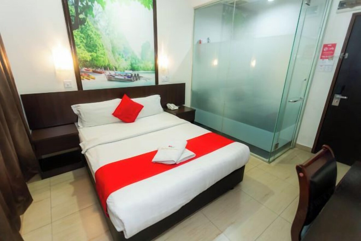 A hotel room with a bed, a nightstand, a glass door, and a wall-mounted TV.