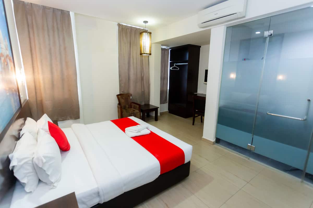 A hotel room with a bed, a chair, a desk, and a walk-in closet.