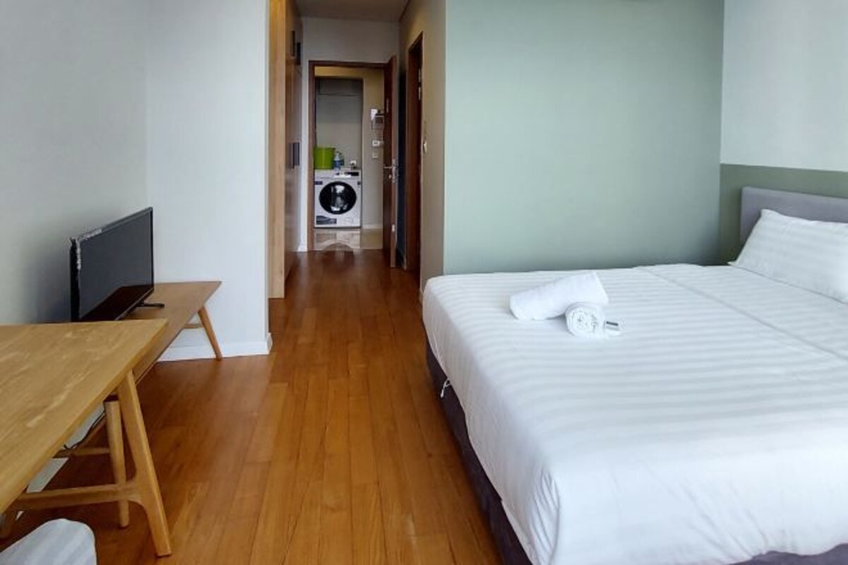 Ein Hotelzimmer mit Holzboden, einem Bett mit weißer Bettwäsche, einem Holztisch und einem Fernseher.