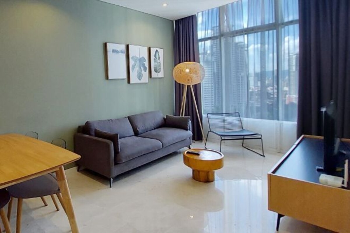 Uma sala de estar moderna com um sofá, uma mesa de jantar, um abajur e um rack para TV.