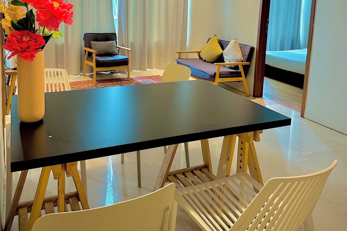 Een moderne eethoek met een zwarte tafel, witte stoelen en twee hanglampen.