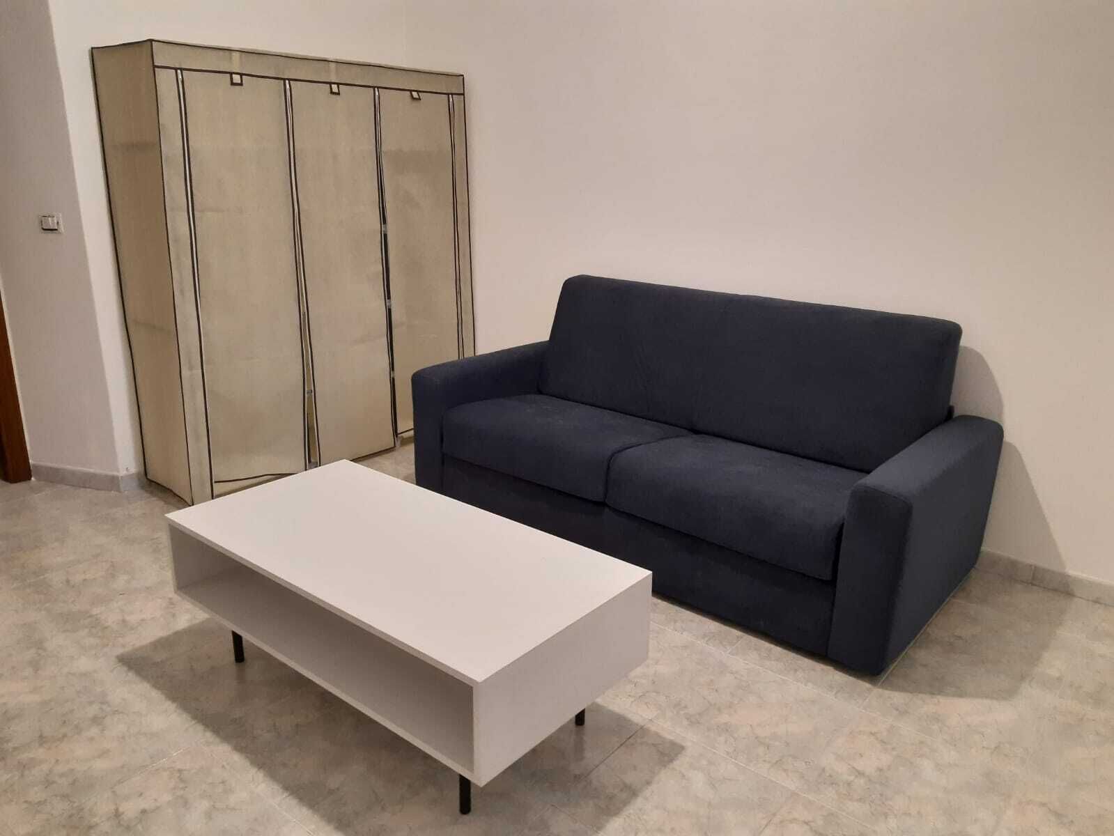 A modern living room with a dark blue sofa, a white coffee table, and a large cabinet.