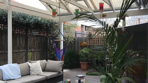 Un patio cubierto con un sofá, una mesa de centro y plantas en macetas.