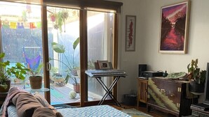 Un dormitorio con cama, escritorio y un ventanal amplio.