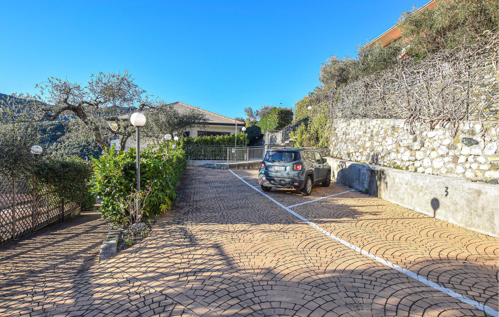 A parking area with a stone wall and a paved walkway leading to a building.