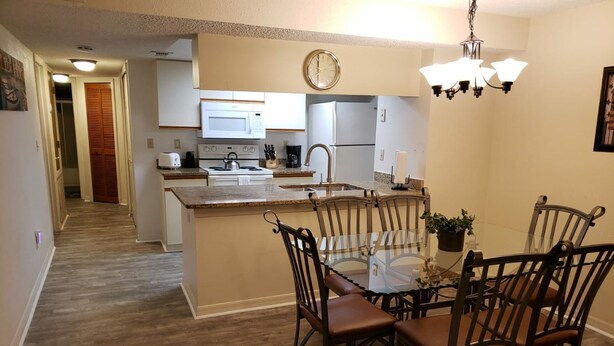 Una cocina moderna con una isla central, una mesa de comedor con sillas y una araña.