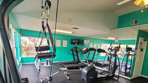 Un gimnasio con equipo de ejercicio, cinta de correr y pared de espejos.