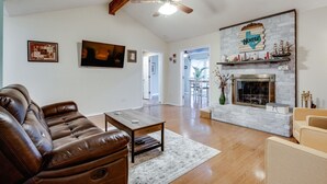 A spacious living room with a leather sofa, a wooden coffee table, a fireplace, and a ceiling fan.