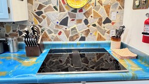 A kitchen with a mosaic backsplash, a gas stove, and a knife block.