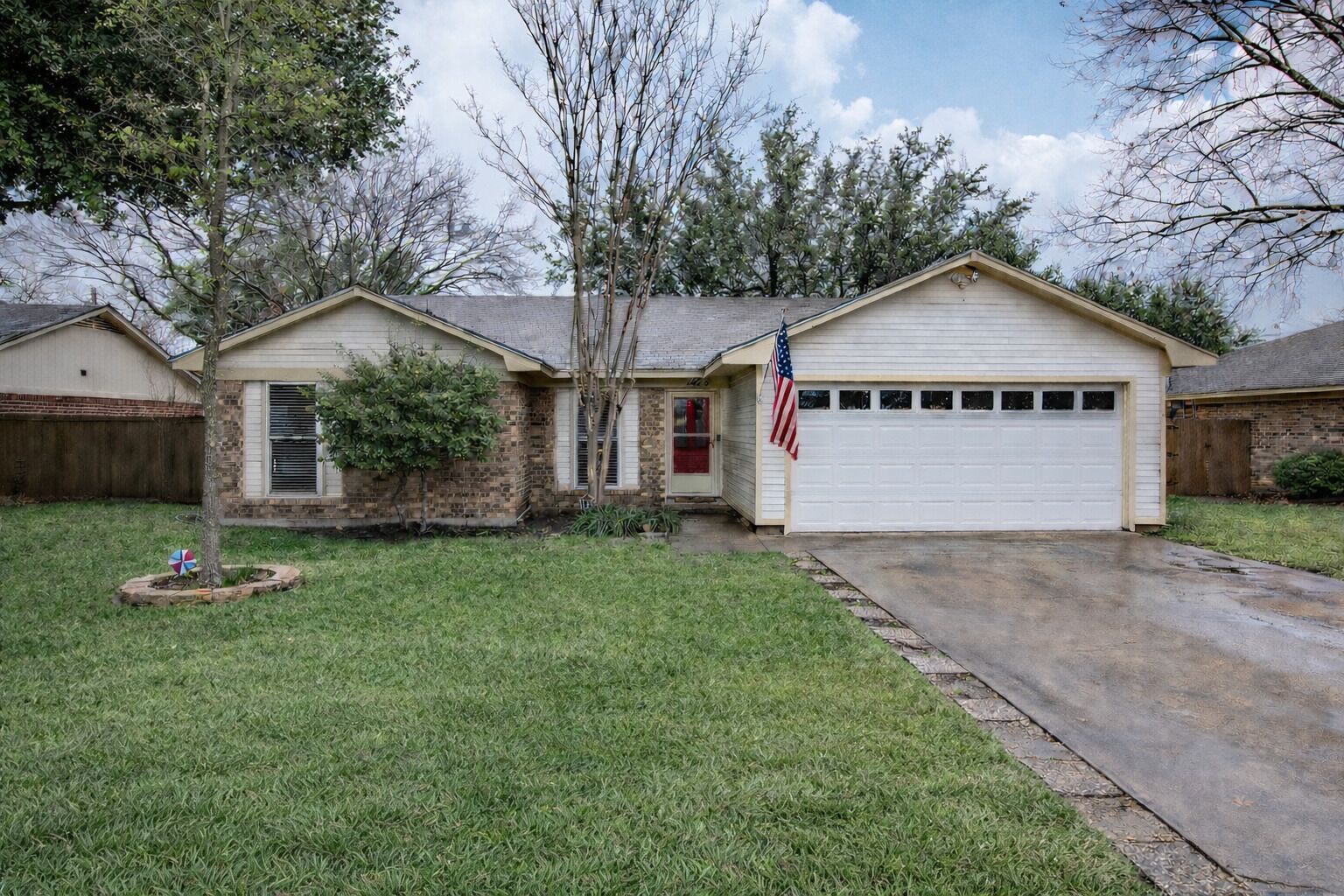 A two-story house with a garage, a front yard, and a small tree.