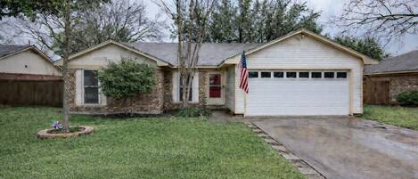 A two-story house with a garage, a front yard, and a small tree.