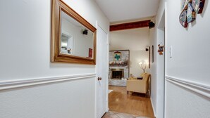 A hallway with a white door, a mirror, a fireplace, and a beige sofa.