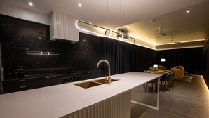 Una cocina moderna con encimera blanca, salpicadero de mármol negro y horno empotrado.