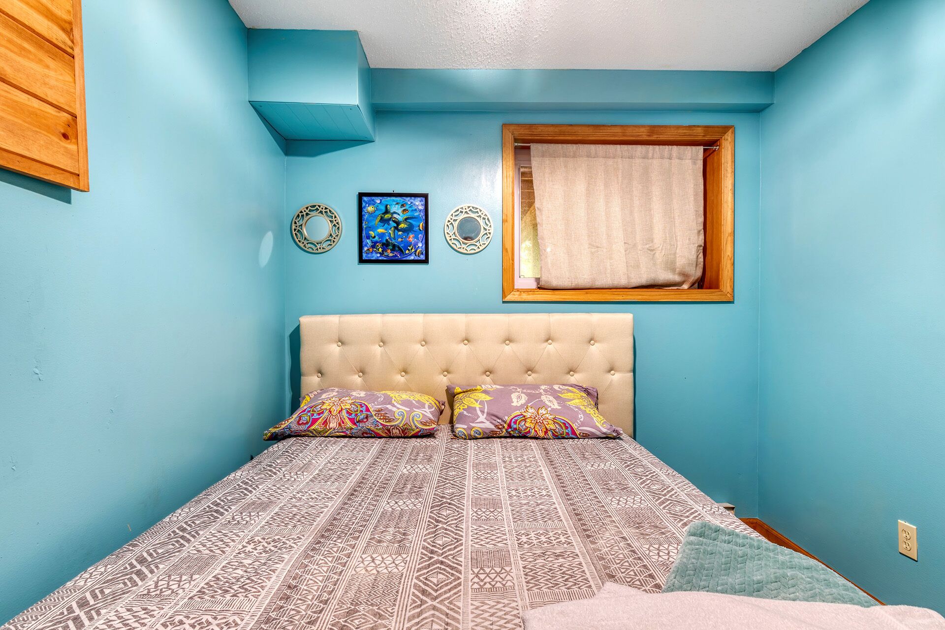 Un dormitorio con una cama, una ventana con cortina y adornos en la pared.