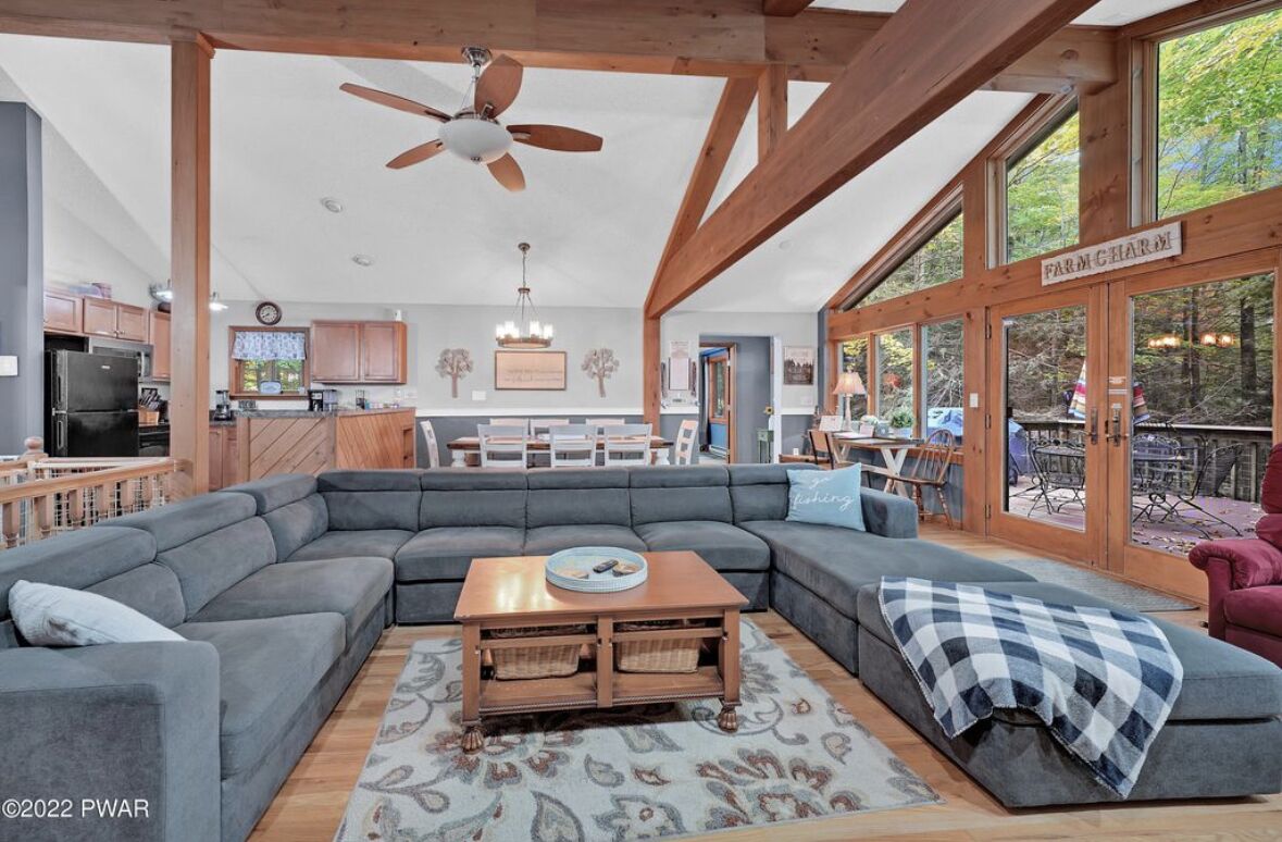 A spacious living room with a large sectional sofa, a wooden coffee table, and a ceiling fan.