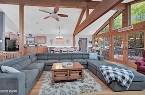A spacious living room with a large sectional sofa, a wooden coffee table, and a ceiling fan. - Cozy Lakefront Home Steps to Pool, Close to Lake & Skiing and All Fun Amenities (Lake Ariel)