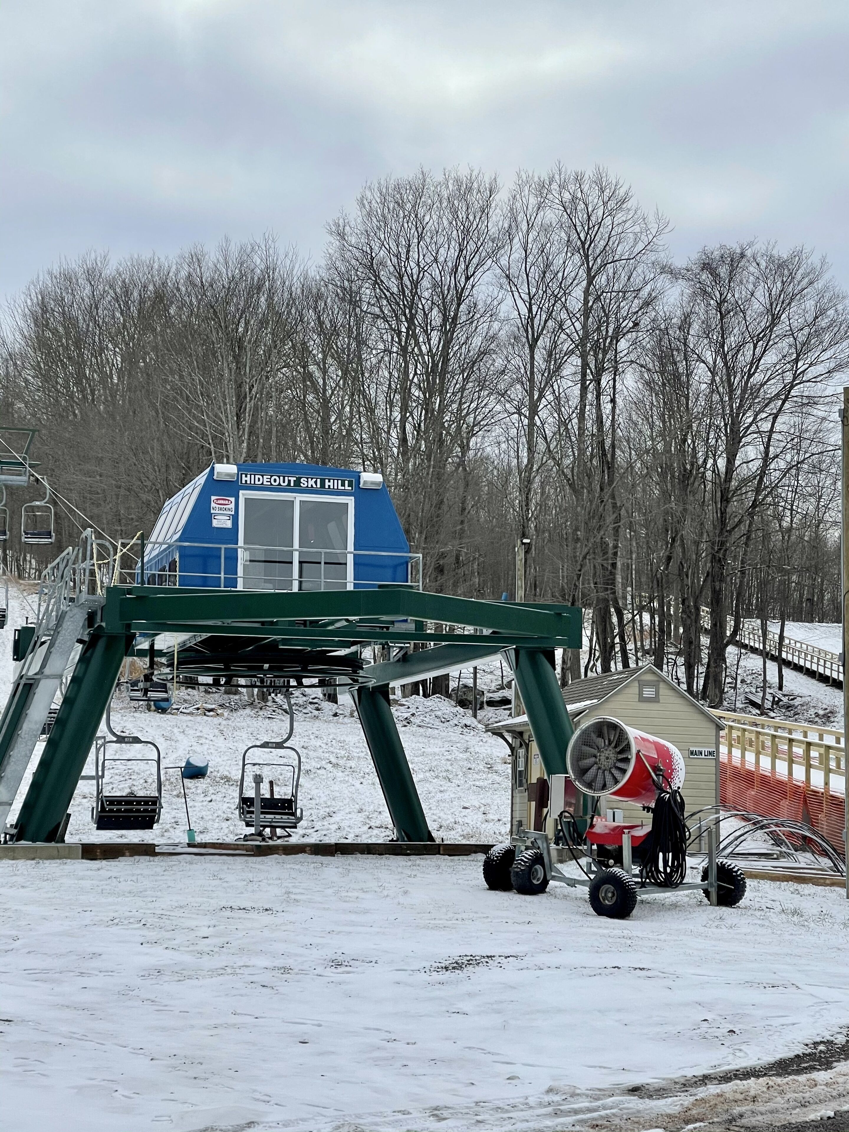 A ski lift station with a blue cabin labeled 'HIDEOUT SKI HILL' and a red and white chairlift.
