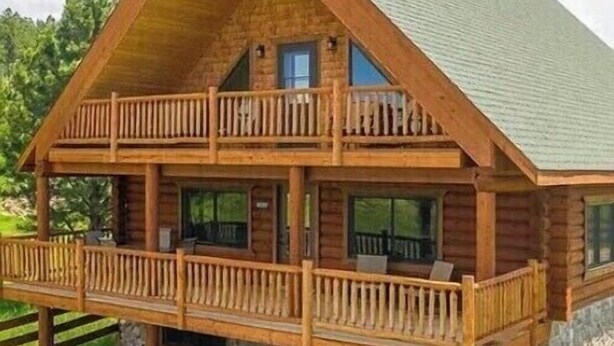 A log cabin with a two-story balcony and a stone foundation. - Peaceful Pines (Custer)