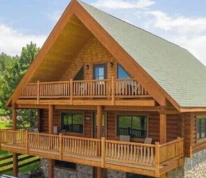 Une cabane en rondins dotée d’un balcon à deux étages et de fondations en pierre.