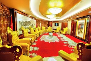 Un salón de conferencias con alfombra roja, sillas doradas y una mesa central.