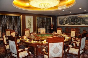 A formal dining room with a round table, chairs, and a chandelier. - Yuan Tong Hotel (Guazhou)