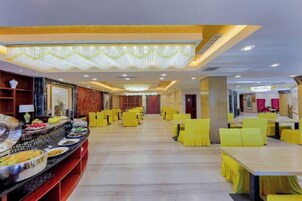 Un comedor de hotel con bufé, sillas amarillas y una mesa larga.
