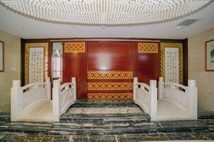Una entrada imponente con suelo de mármol, techo decorativo y paneles de madera tradicionales.