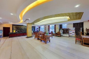 Un vestíbulo de hotel con mostrador de recepción, zona de estar y un ventanal grande.