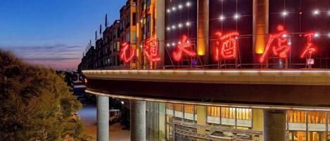 A hotel with a prominent illuminated sign, large windows, and a modern architectural design.