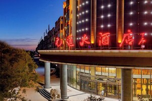 Un hotel con un llamativo letrero iluminado, amplias ventanas y un diseño arquitectónico moderno.