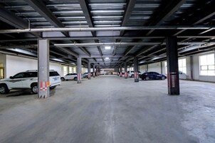 Un estacionamiento de varios niveles con pisos de concreto y vigas de metal.