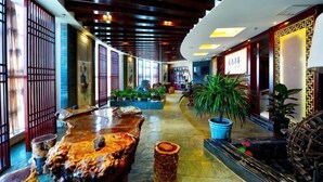 Een hotel lobby met een houten plafond, een fontein in het midden, potplanten en traditionele decoratie.