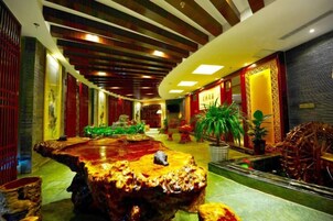 Un vestíbulo de hotel con una gran mesa de madera, zona de estar y plantas decorativas.