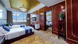 Een hotelkamer met twee bedden, een kroonluchter, een groot raam en een decoratief wandpaneel.