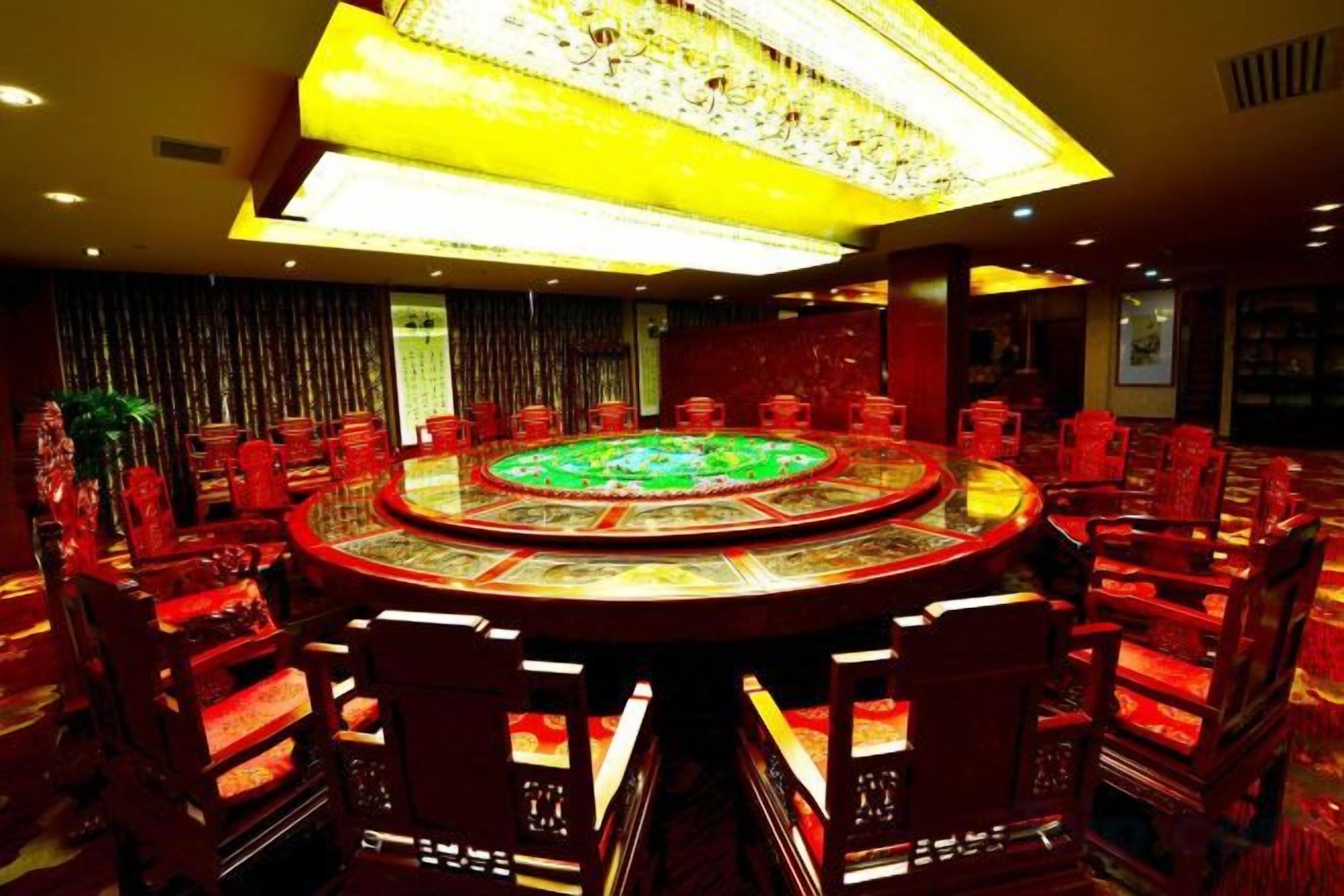 A round table with chairs, a chandelier, and a patterned carpet.