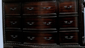 Een donkere houten dressoir met zes lades en een grote spiegel erboven.